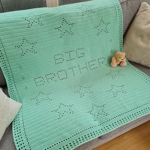 May include: A light green crocheted baby blanket with a white border and the words "Big Brother" in the center. The blanket is decorated with white crocheted stars.