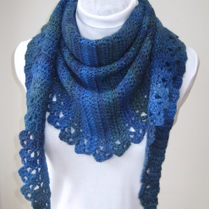May include: A blue and green crocheted scarf with a scalloped edge. The scarf is draped over a white mannequin.