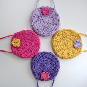 May include: Four crocheted purses with flower embellishments. The purses are in shades of purple, pink, and yellow.