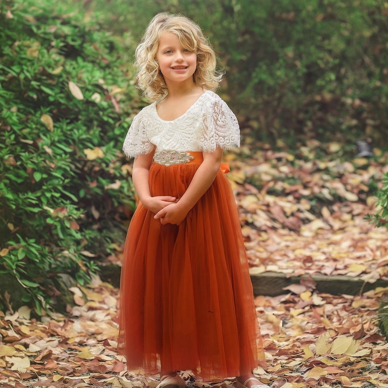 burnt orange flower girl dress in tulle and lace. White lace short sleeves and full length tulle bottom for special occasions.