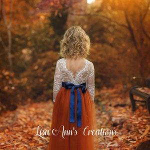 Flower girl dress in burnt orange tulle with navy blue sash, white lace long sleeve top