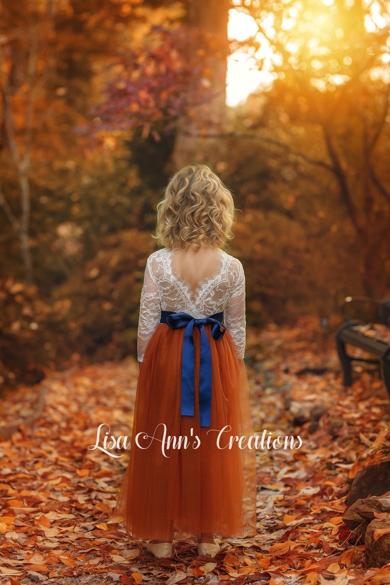 Flower girl dress in burnt orange tulle with navy blue sash, white lace long sleeve top