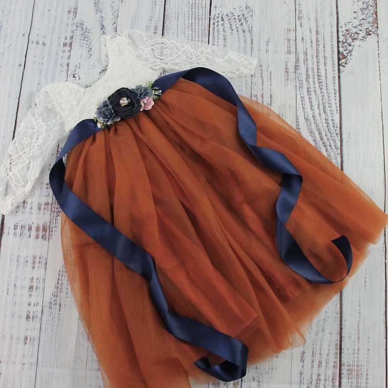 jr bridesmaid dress in burnt orange tulle full length with long sleeve white lace bodice and navy flower sash