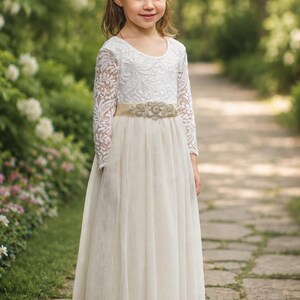 Ivory flower girl dress with long lace sleeves, layered tulle skirt and decorative sash.