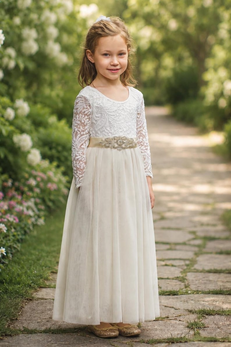 Ivory flower girl dress with long lace sleeves, layered tulle skirt and decorative sash.
