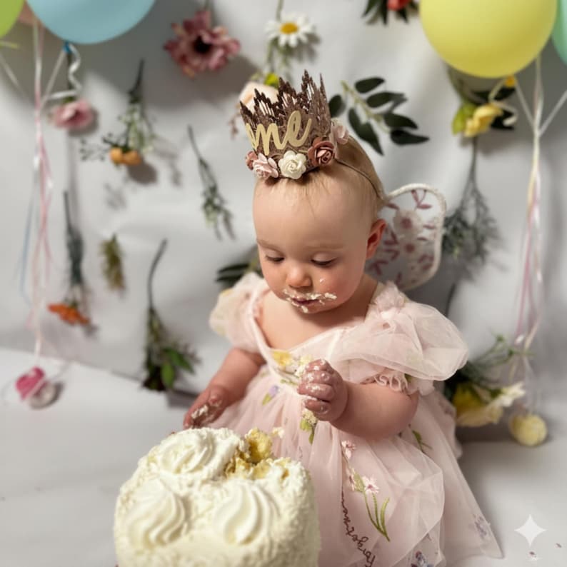 First birthday dress in a light pink floral for a wildflower theme. Capture the charm of a baby girls floral dress in puffy shorts sleeves and a built in bodysuit.