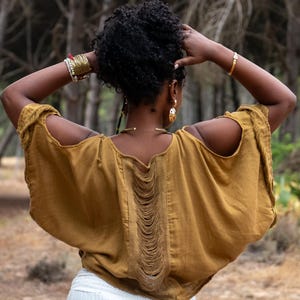 Top bohemio de algodón con hombros descubiertos, detalle de flecos y corte fluido. Talla única.
