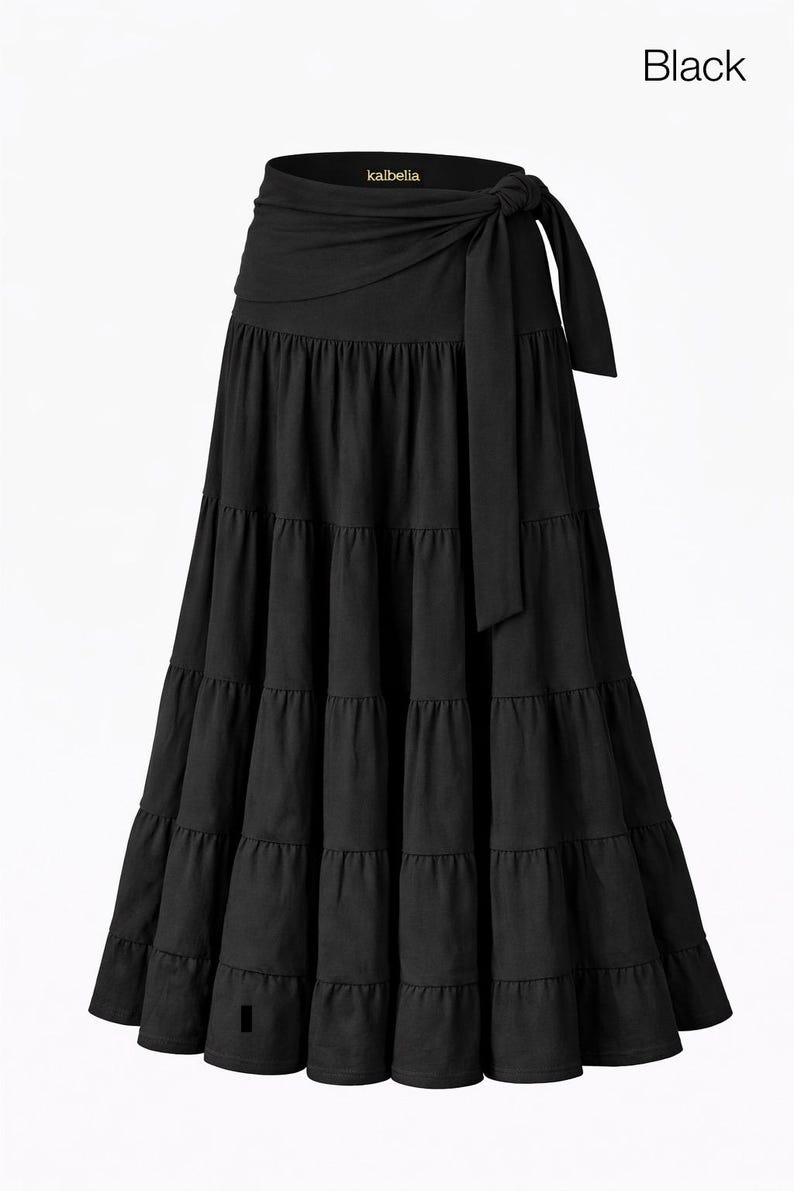 May include: Black tiered maxi skirt with a wrap tie. The skirt features a high waist and a flowing, tiered design. The brand name "kalbella" is visible on the waistband. The word "Black" is in the upper right corner.