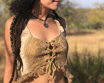May include: A beige crop top featuring a central lace panel with a brown lace-up corset-style front closure, thin shoulder straps, and a frayed hemline. The garment is constructed with a smooth fabric side panel and a textured lace front section.