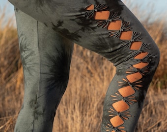 May include: Dark green tie-dye leggings with decorative cutouts along the side of the leg. The leggings have a unique design with a tie-dye pattern and a series of diamond-shaped cutouts.