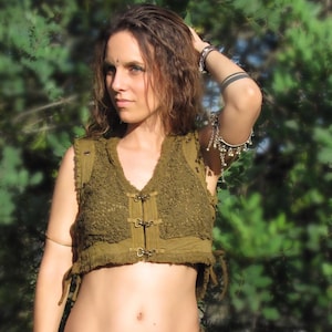 Op de afbeelding: Een groen gecrochet vest met een kantontwerp en een voorsluiting met metalen gespen. Het vest is gecropped en heeft een franje detail rond de halslijn.