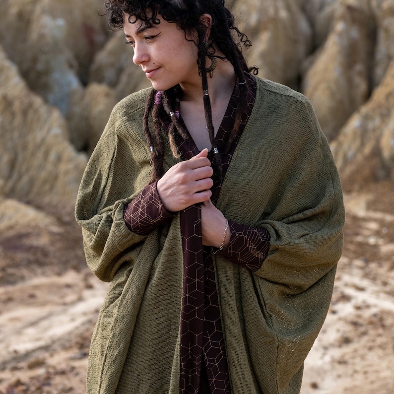 May include: A green knitted cardigan with a brown geometric pattern lining. The cardigan has a relaxed fit and long sleeves.