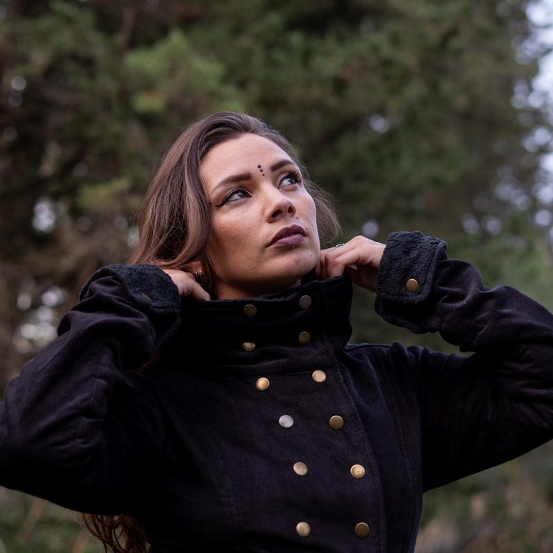 May include: A black jacket with a high collar and gold buttons. The jacket is made of a soft, comfortable fabric and has a relaxed fit.
