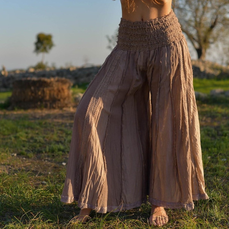 May include: A pair of wide-legged pants in a light brown color with a gathered elastic waistband. The pants have a flowing, relaxed fit and are made of a soft, lightweight fabric.