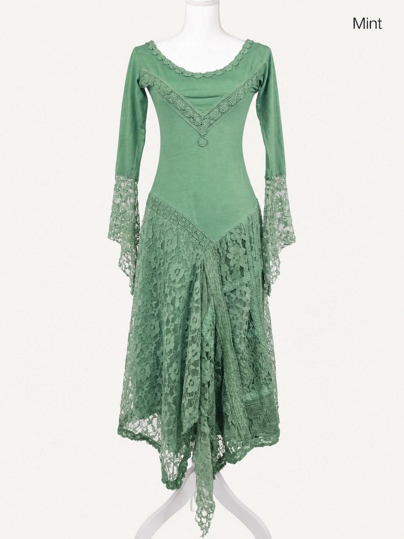 Op de afbeelding: Een mintgroene jurk met lange mouwen, een ronde halslijn met kanten afwerking, een V-vormige kanten overlay op het lijfje en uitlopende kanten manchetten. De rok is gemaakt van gelaagd bloemenkant met een asymmetrische zoom en een punt.