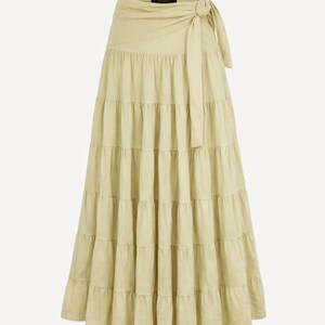 May include: A beige, tiered maxi skirt with a wrap-around waist and tie closure. The skirt has a flowing, layered design and is made of a light-colored fabric. The word "Beige" is in the upper right corner.