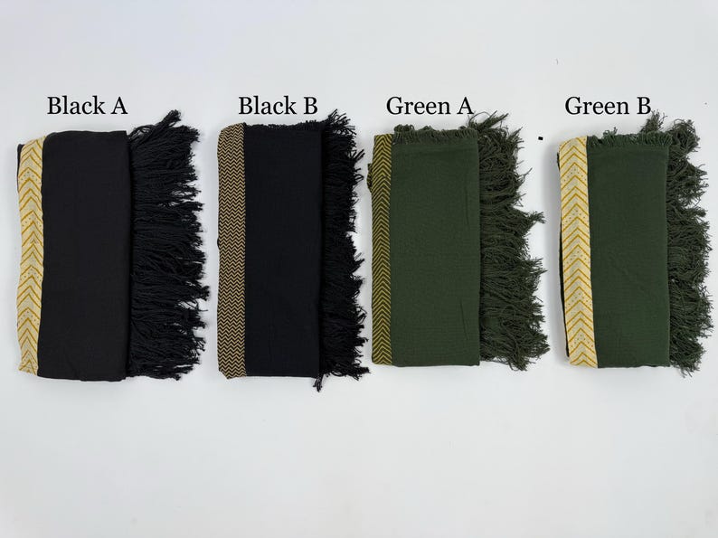 May include: Four folded scarves in black and green, each with a decorative border and fringe. The scarves are labeled "Black A", "Black B", "Green A", and "Green B". The borders feature gold and tan chevron or geometric patterns.
