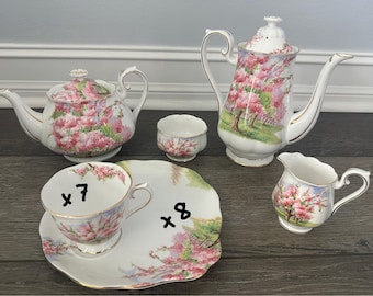Può includere: Un servizio da tè vintage con teiera, caffettiera, lattiera, zuccheriera, tazza da tè e piattino. Il set è decorato con un motivo floreale rosa e finiture dorate. Il set include 7 tazze e 8 piattini.