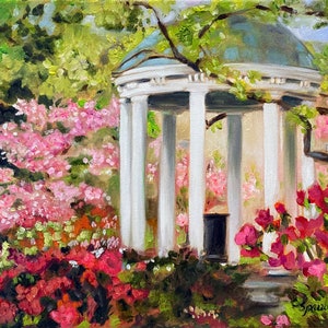 May include: A white, columned gazebo with a green roof surrounded by pink and red flowers. The gazebo is in a garden setting with green trees in the background.