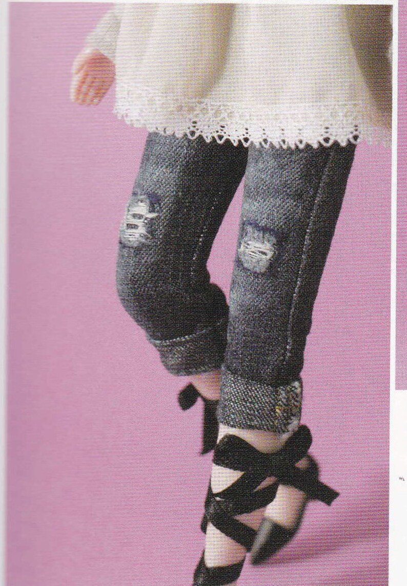 May include: A pair of dark blue denim jeans with distressed details and cuffed hems. The jeans are paired with black ribbon-tied shoes.