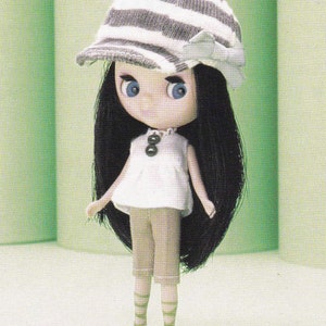 May include: A doll with long black hair wearing a white and gray striped hat, a white shirt, and brown pants.