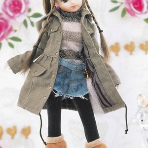 May include: A doll wearing a brown and gray striped sweater, a green jacket, blue denim shorts, black tights, and brown fur boots. The doll has long brown hair in braids and is wearing a brown bow.