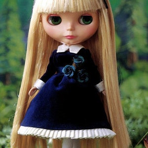 May include: A doll with long blonde hair wearing a blue dress with white lace trim and a black bow. The doll has blue eyes and is wearing white socks and black shoes.