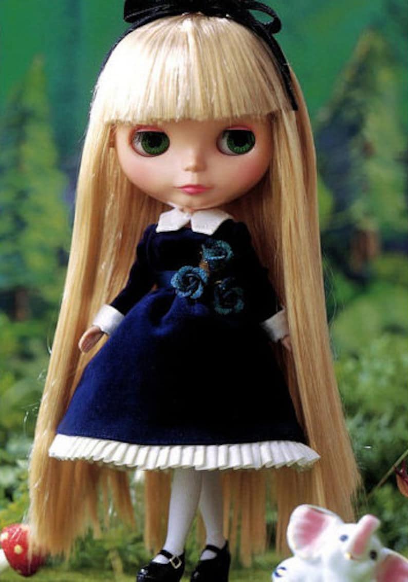 May include: A doll with long blonde hair wearing a blue dress with white lace trim and a black bow. The doll has blue eyes and is wearing white socks and black shoes.