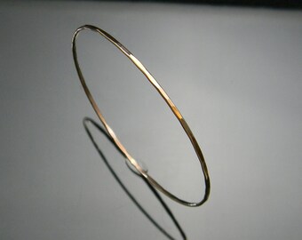 May include: A simple gold bangle bracelet with a hammered finish.
