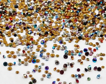 Puede incluir: Un gran surtido de piedras de cristal de colores en varios tamaños y formas. Las piedras de cristal están esparcidas sobre una superficie blanca.