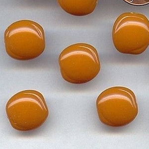 May include: A collection of 12 amber glass beads, each with a slightly rounded square shape. The beads are arranged in a scattered pattern on a light gray surface. A penny is included for size reference.