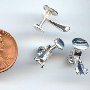 May include: Three silver earring backs, each with a screw-on design. The earring backs are approximately the size of a US penny.