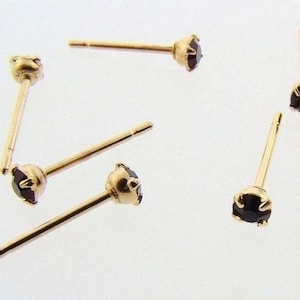 Könnte beinhalten: Fünf Paar goldene Ohrstecker mit schwarzen Edelsteinen. Die Ohrringe sind schlicht und elegant.