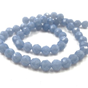 May include: A strand of light blue faceted gemstone beads. The beads are round and have a smooth, polished finish.