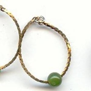 May include: A pair of gold hoop earrings with green stone accents. The earrings are about the size of a US penny.