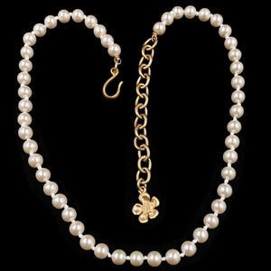 May include: A white pearl necklace with a gold chain extender and a small gold flower charm.