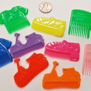 May include: A set of nine colorful plastic combs with different designs, including a shirt, a scooter, and a shoe. The combs are all about 4 inches long and have a comb on one side and a design on the other.