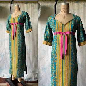 May include: A long, teal blue dress with a floral print and a pink ribbon sash. The dress has a square neckline and 3/4 sleeves.