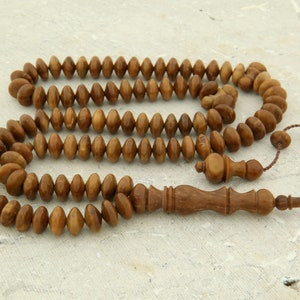 May include: A brown wooden prayer beads or rosary with a tassel. The beads are oval shaped and have a natural wood grain. The tassel is made of brown cord and has a small wooden bead at the end.