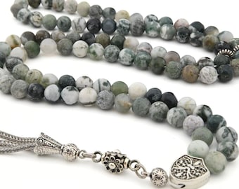 Può includere: Una collana di perline con perline rotonde e screziate nei toni del verde, grigio e bianco. La collana ha un nappa argentata e una chiusura decorativa. Le perline hanno un diametro di circa 8 mm.