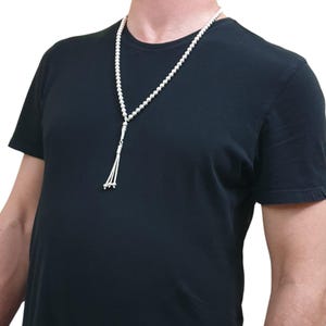 May include: A silver prayer beads necklace with a tassel. The beads are round and the tassel is made of multiple strands of silver.