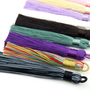 May include: Assortment of colorful silk tassels in various colors, including black, green, purple, rainbow, and gray. The tassels are made of soft, silky threads and have a decorative knot at the top.