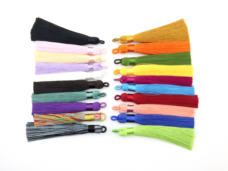 May include: Assortment of 18 colorful tassel trims with gold, orange, green, yellow, purple, blue, red, pink, and black colors. The tassels are made of soft, silky fabric and have a loop at the top for easy attachment.