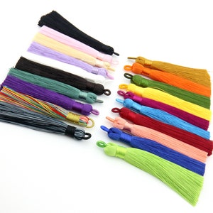 May include: Assortment of 16 colorful silk tassels with a variety of colors including black, pink, beige, purple, white, green, purple, grey, yellow, orange, blue, red, and light pink.