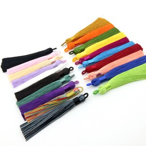 May include: Assortment of 15 colorful silk tassels with various lengths. The tassels are made of soft, silky material and have a variety of colors, including black, white, pink, purple, green, blue, red, yellow, and orange.