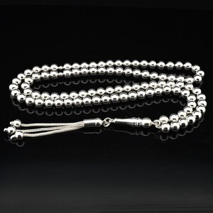 May include: A silver prayer beads necklace with a silver tassel. The beads are round and smooth.