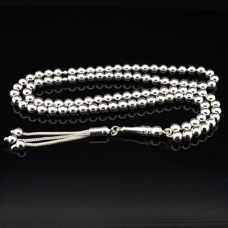 May include: A silver prayer beads necklace with a silver tassel. The beads are round and smooth.