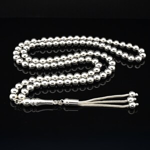 May include: A silver prayer beads necklace with a silver tassel. The beads are round and smooth.