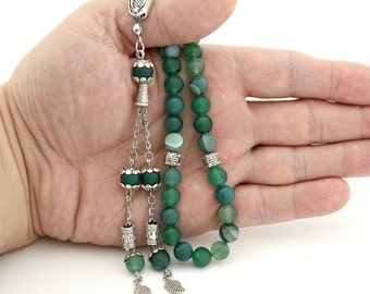 Può includere: Grani di preghiera in agata verde con dettagli argentati, tra cui un ciondolo a forma di mezzaluna, un nappa e ciondoli a forma di foglia.