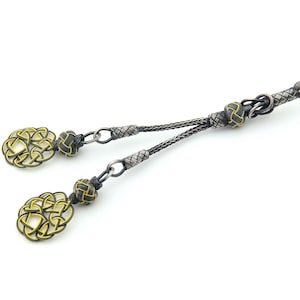 May include: A black and gold prayer beads with a knotted cord and decorative ends. The beads are made of a woven material with a silver finish.